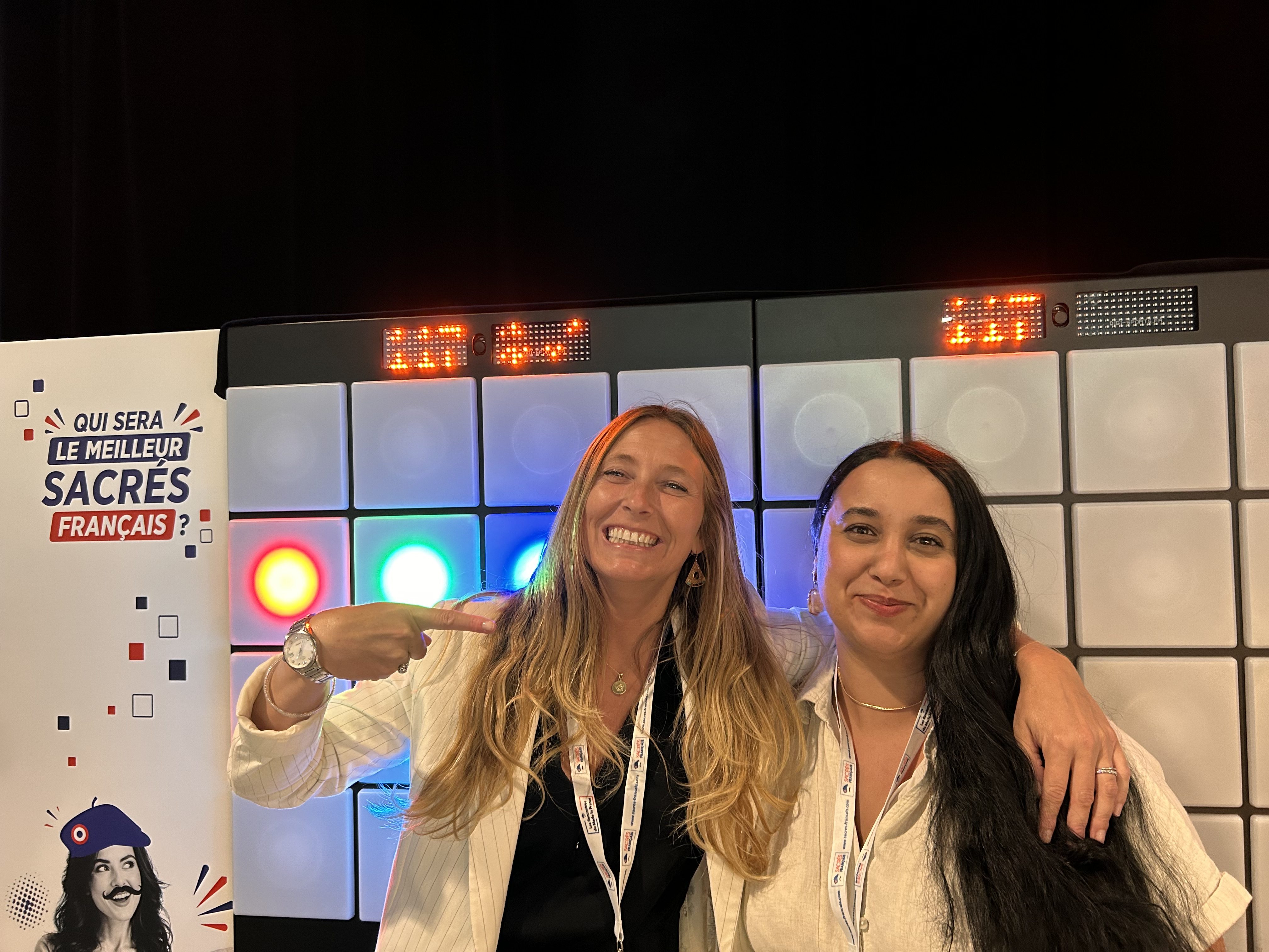 Le Mur Interactif Provence est en fond avec deux amies qui viennent de s'affronter dans un duel convival avec un jeu de réflexe.